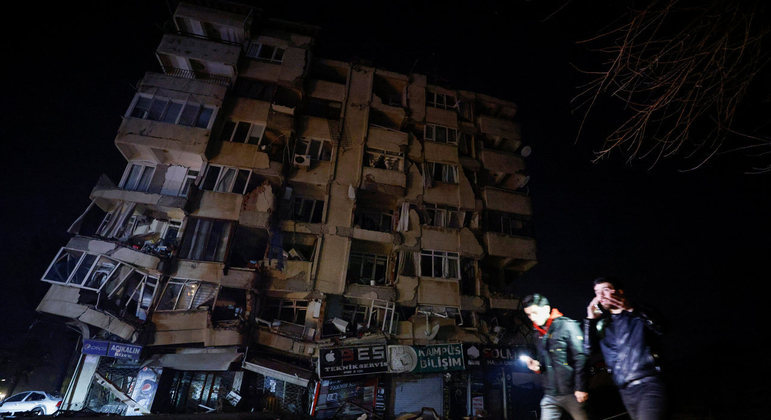 Civis passam em frente a um prédio destruído pelo terremoto em Antakya, cidade em que fica a sede do 
Hatayspor