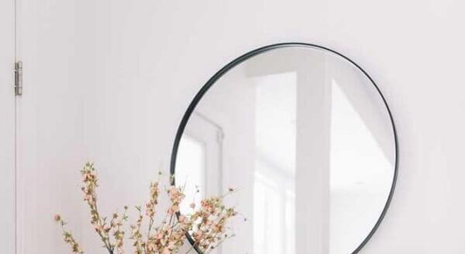 aparador minimalista decorado com puffs e espelho redondo