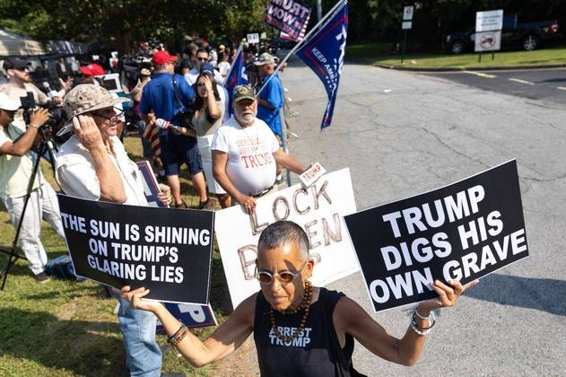 Uma única pessoa que se manifestava contra Trump foi fotografada em meio aos apoiadores do ex-presidente. Na foto, ela segura dois cartazes com os seguintes dizeres: 