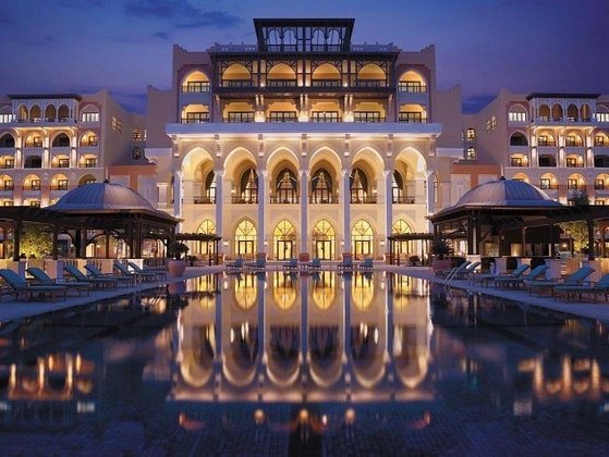 Área externa mostrando a arquitetura de um palácio árabe, com direito a piscina.