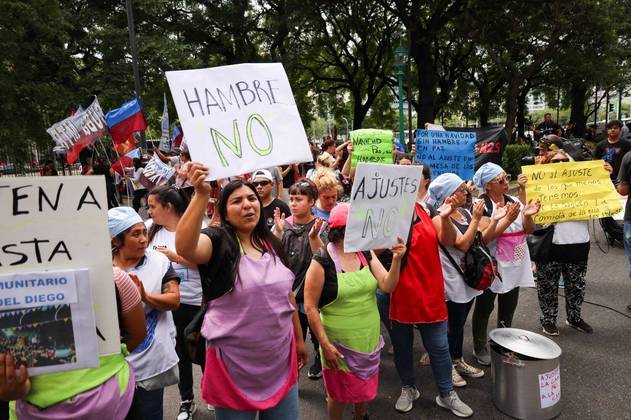 Os argentinos foram às ruas de Buenos Aires nesta sexta-feira (22) para protestar pelo segundo dia contra as medidas econômicas anunciadas pelo novo presidente, o ultraliberal Javier MIlei. Na foto, manifestantes gritam enquanto seguram cartazes, entre eles um que diz 