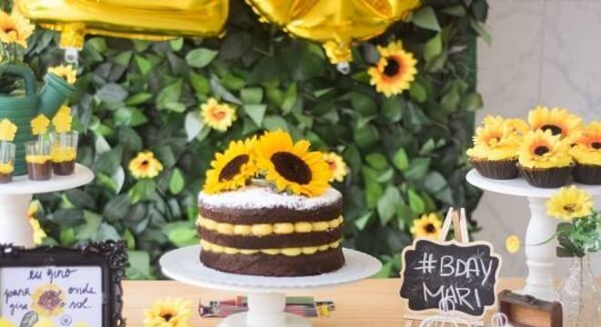 As flores foram espalhadas por toda a mesa do bolo da festa tema girassol