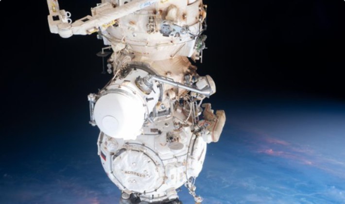 Dois astronautas no momento em que saem de uma estação espacial para instalar equipamentos e recuperar experimentos; a caminhada durou cerca de sete horas 