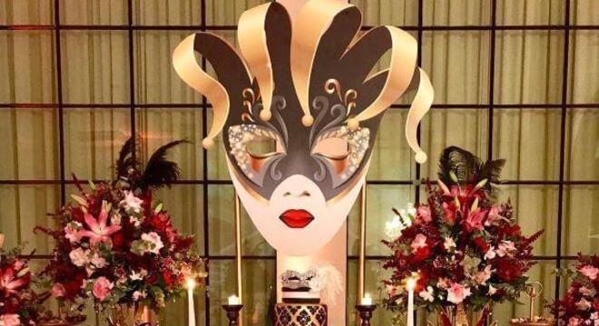Baile de máscaras com decoração dourada e flores vermelhas