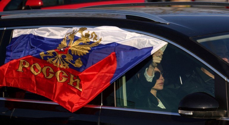 Mulher leva bandeira da Rússia em protesto pró-guerra