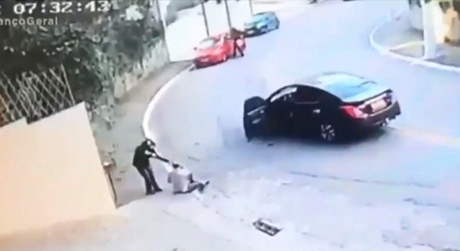 Bandido em moto rende motorista em rua do Morumbi; ao fundo, outro ladrão assalta motorista em um carro vermelho