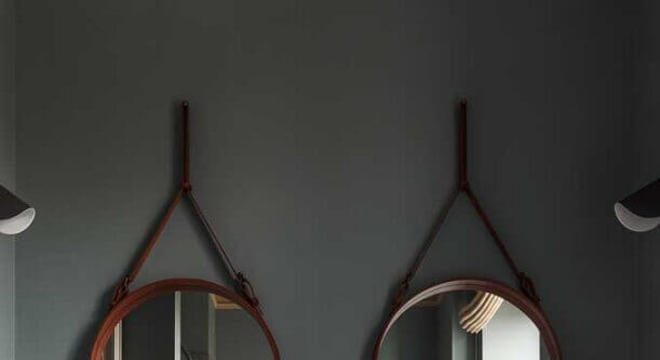 banheiro decorado com parede cinza e dois espelhos redondos 