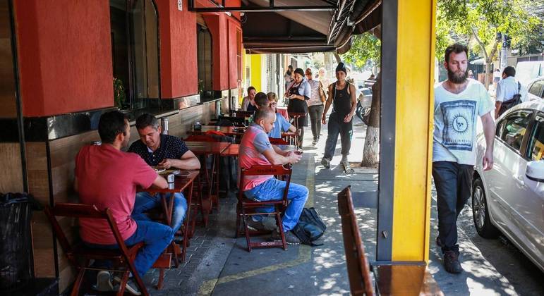 Bar ocupa parcialmente calçada com mesas em Pinheiros, zona oeste de SP