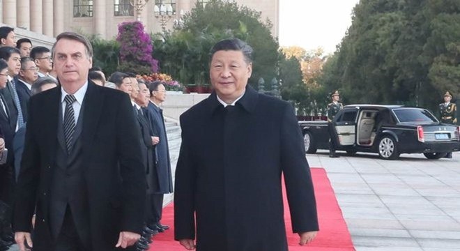 Xi Jinping e Bolsonaro em cerimonia oficial em Pequim; ao fundo, a luxuosa limusine que trouxe o brasileiro
