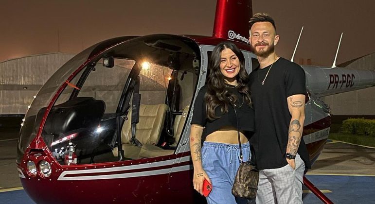 Bianca Andrade e Fred em frente ao helicóptero que caiu em São Paulo