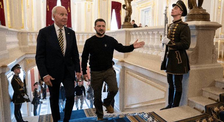 Biden e Zelenski sobem as escadas dentro do Palácio Mariinsky, em Kiev, capital da Ucrânia