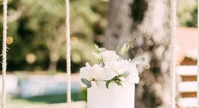 bolo de casamento branco decorado com folhas e flores 