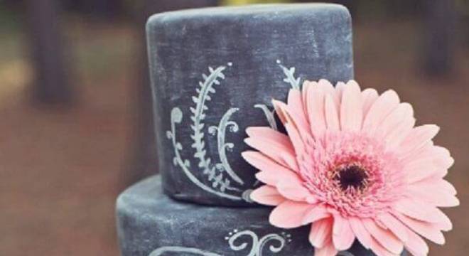 Bolo fake lousa com fundo preto e acabamento feito com flor de gérbera rosa