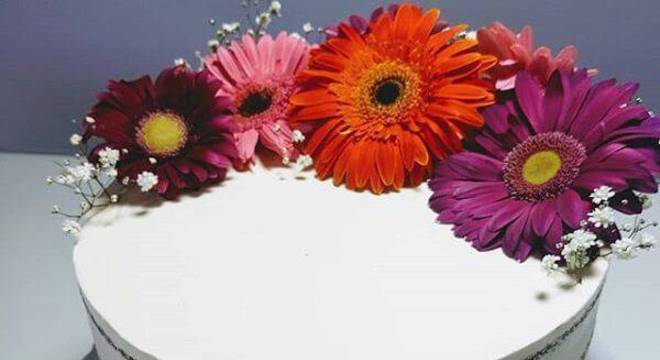 Bolo simples com topo formado por flores de gérbera