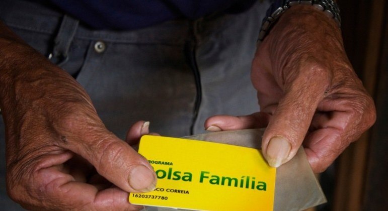 Beneficiário com cartão do Bolsa Família nas mãos