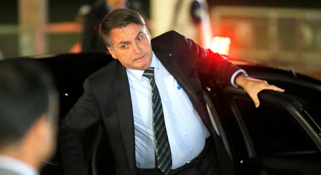 O presidente Jair Bolsonaro perde o equilíbrio e se apoia ao descer do carro