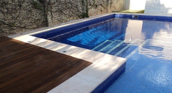 Borda de piscina com pedra e piso de madeira