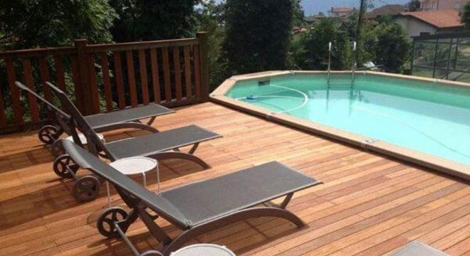 Borda de piscina de madeira com deck e espreguiçadeiras