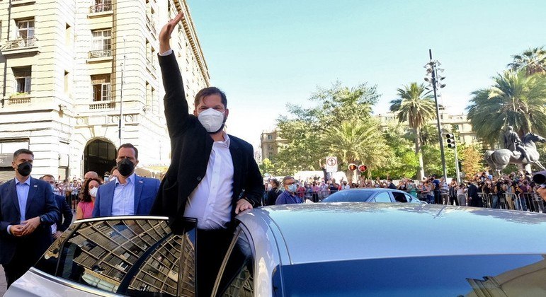 Gabriel Boric acena para apoiadores de um carro na praça principal de Santiago