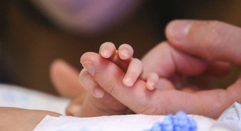 Mão de um recém-nascido segura o dedo de um adulto