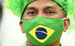 Torcedor usa uma máscara com a bandeira brasileira e se protege da Covid enquanto apoia a seleção no Catar