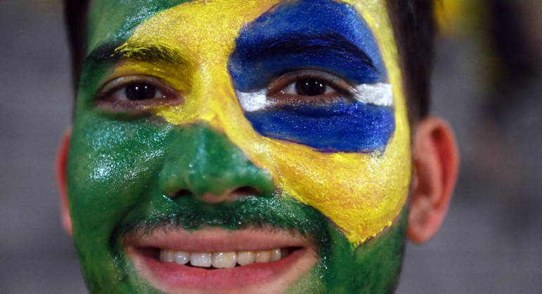 Torcedor pinta a bandeira brasileira no rosto para acompanhar a seleção contra Camarões no estádio de Lusail