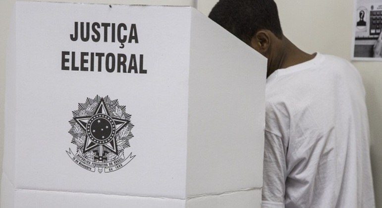 Jovem em cabine de votação
