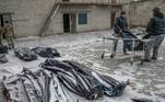 Dois homens carregam um cadáver em um saco para colocá-lo ao lado de outros em um pátio coberto de neve em Mykolaiv, uma cidade às margens do Mar Negro que está sob ataque russo há dias 