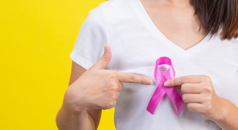 Mulher segurando um laço rosa que representa a luta contra o câncer de mama