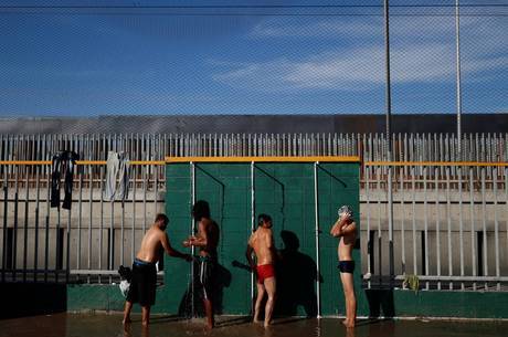 Refugiados tomam banho em chuveiros improvisados