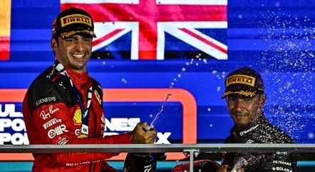 Carlos Sainz comemora a vitória, ao lado de Lewis Hamilton