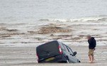 Um turista que não seguiu as regras de transporte em uma praia britânica acabou obrigado a assistir enquanto a van dele afundava na areia. A cena foi registrada por um fotógrafo amador, que agressivamente chamou o homem de 