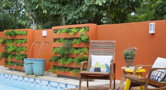 Casa com muro laranja, piscina e jardim vertical