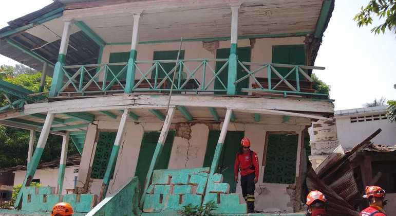 Militares dos bombeiros inspecionam casa destruída por terremoto no Haiti.