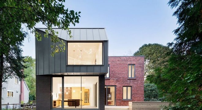 casa em l com paredes de vidro e parede de tijolinho