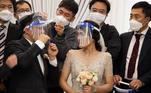 Em Seul, capital da Coreia do Sul, o sul-coreano Chang Seung-yun e sua noiva vietnamita Nguyen Thi Ut posam com alguns convidados após a cerimônia de casamento com medidas de segurança devido à pandemia do coronavírus