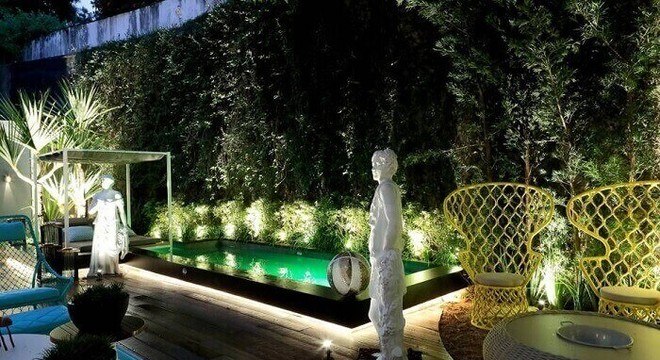 Casas com piscinas iluminadas com deck de madeira