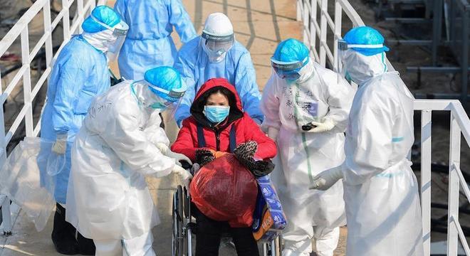 Profissionais de saúde transportam paciente infectada pelo coronavírus em Wuhan