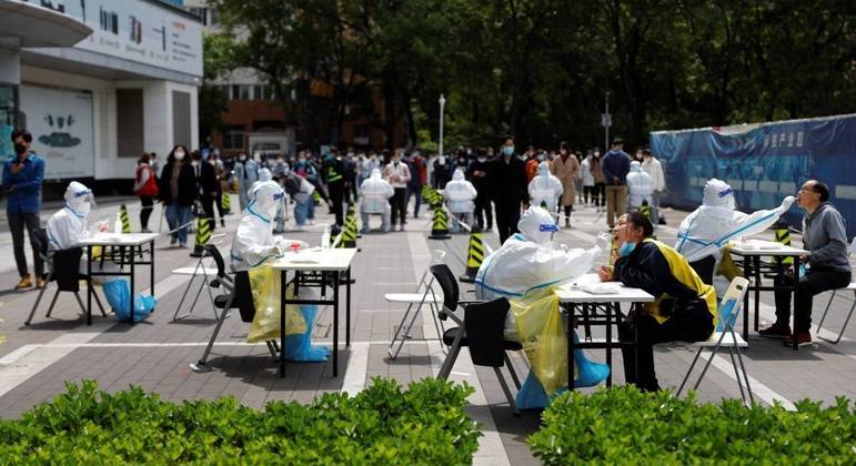 Trabalhadores em trajes de proteção coletam testes de Covid-19 em Pequim 