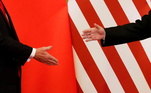 Montagem mostra as mãos de Xi Jinping e Donald Trump sobre as bandeiras da China e dos EUA