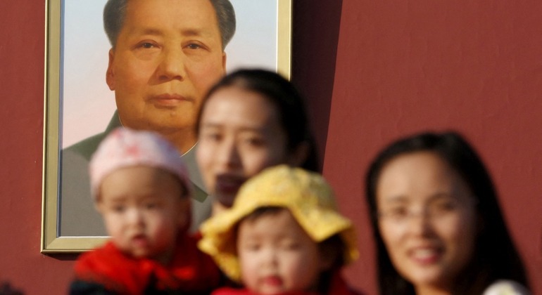 Mulheres e seus bebês posam para fotos em frente ao retrato do falecido presidente chinês Mao Zedong