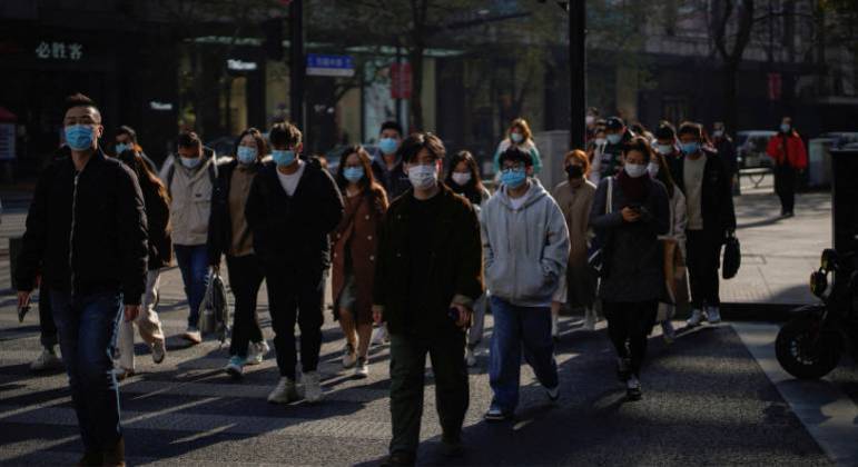 Pedestres caminham em Xangai, na China, em meio à pandemia de Covid-19
