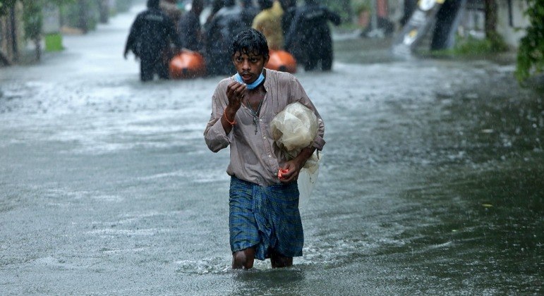 Um homem caminhando em meio à inundação causada por fortes chuvas em Chennai, na Índia