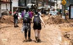 Pessoas sujas de lama caminham pelas ruas de Petrópolis, na região serrana do Rio, nesta quarta-feira (16), após a cidade de devastada por fortes chuvas que deixaram dezenas de mortos