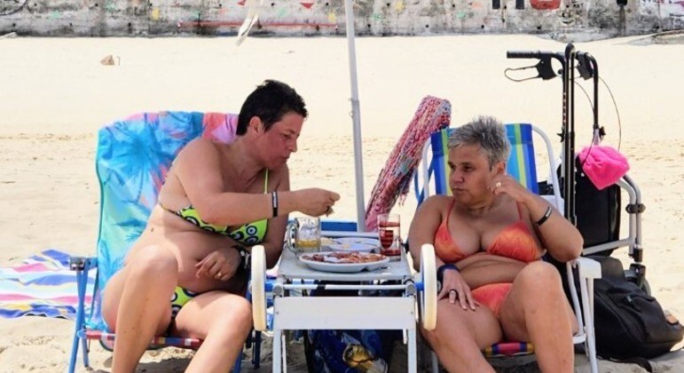 Claudia Rodrigues e Adriane Bonato comem petiscos em praia no Rio