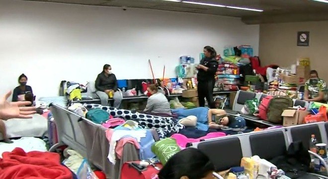 Grupo divide espaço do aeroporto com roupas colchões, malas e toalhas