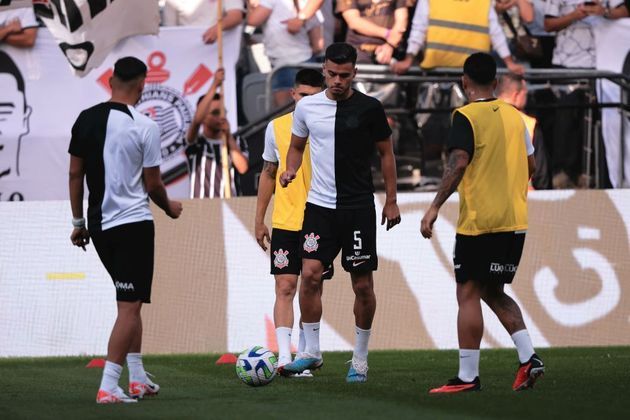 Atletas corintianos no gramado da Neo Química Arena se preparam para a partida contra o Palmeiras