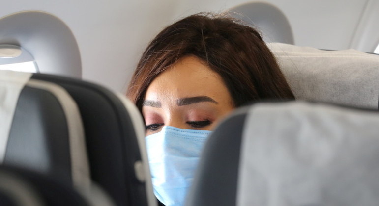 Passageira com máscara a bordo de avião; nos EUA, uso não é mais obrigatório
