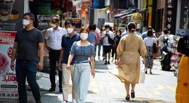 Pessoas com máscara no rosto caminham por rua de Seul, capital da Coreia do Sul