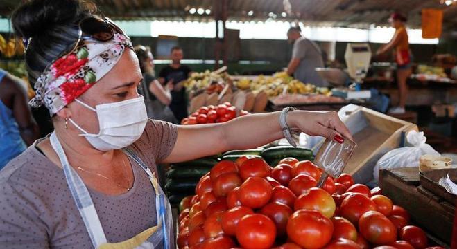 Mulher usa máscara para proteger-se do coronavírus em mercado de Havana
